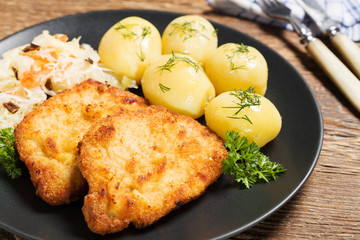 Fried pork chop in breadcrumbs, served with boiled potatoes and
