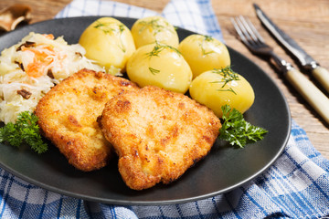 Fried pork chop in breadcrumbs, served with boiled potatoes and