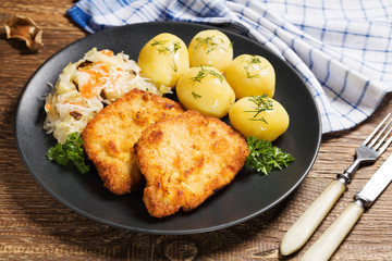 Fried pork chop in breadcrumbs, served with boiled potatoes and