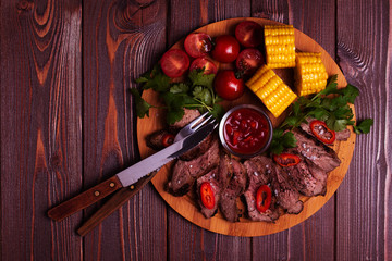 BBQ lamb steak with vegetable and herb on dark wooden background