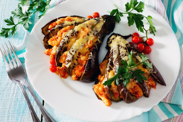 Baked eggplant with cheese, tomatoes and chicken on a wooden tab