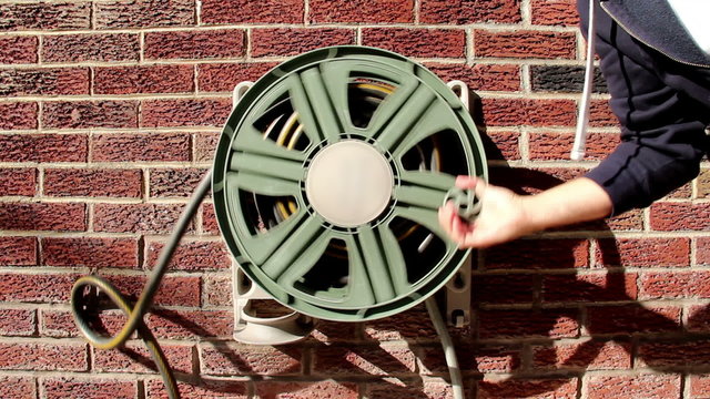 Winding-up a household garden hose. 