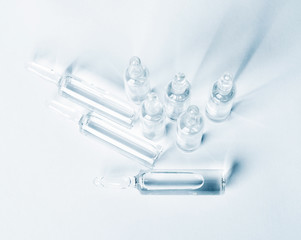 Top view of break-seal glass ampoule set with liquid medicine on light blue background.