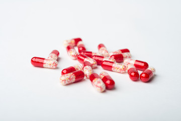 A heap of red medicine capsules on white surface.