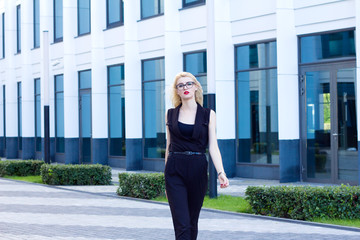 Obraz premium Intelligent woman walks down the street against the background of the business center