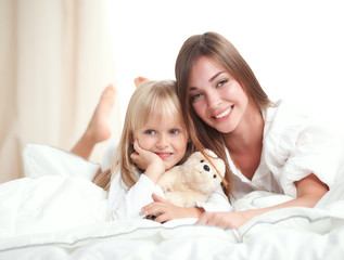 Woman and young girl lying in bed smiling