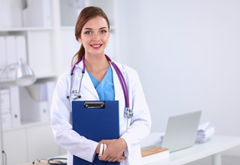 Smiling female doctor with a folder in uniform standing at