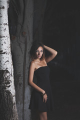 Young women in black dress. Fashion posing in the night forest. 