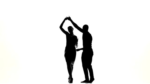 Two latino dancers in action, silhouette, on white, slow motion