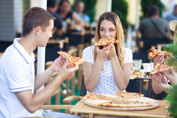 Group of young people eating pizza in a restaurant
