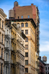 Fototapeta na wymiar Cornices and fire escapes with wooden water towers of Soho loft buildings, Manhattan, New York City