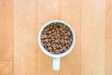 Coffee beans in a cup on wooden floor