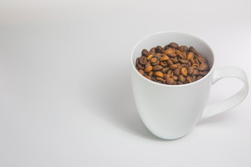 Coffee beans in a cup on white background