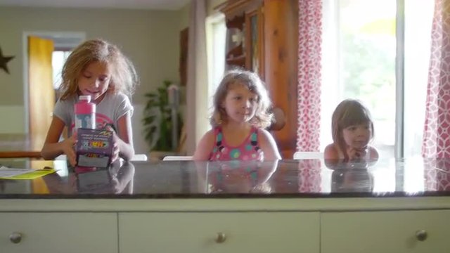 Three girls sitting at a kitchen counter in the morning
