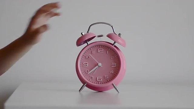 Alarm clock ringing child comically turning ringing bell off