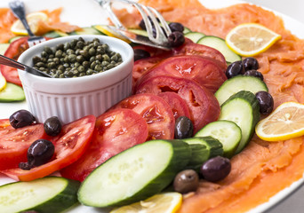 Deli platter with smoked salmon, tomatoes, cucumbers, olives and capers