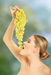 Side view of nude woman eating grapes