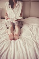 ベッドの上で本を読む女性