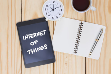 Blank notebook and tablet with Internet of things (IoT) word on