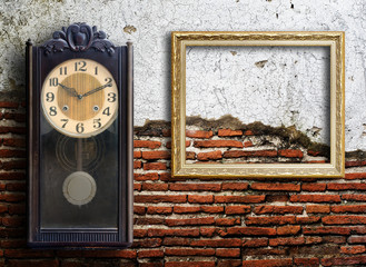 Old clock and empty picture frame on wood wall.