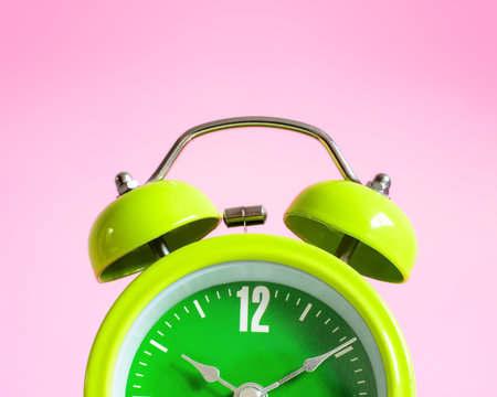 Alarm clock on pink background.