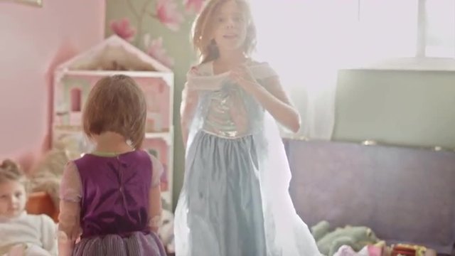 Two little girls wearing princess dresses playing together
