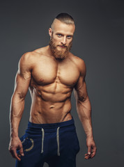 Shirtless bodybuilder with beard posing.