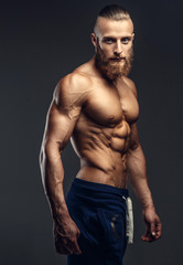 Shirtless bodybuilder with beard posing.