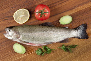 gutted fish trout on a cutting board with vegetables