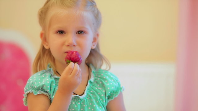 Adorable little girl eating strawberries