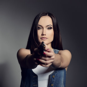 Beautiful girl with gun, tudio shot.