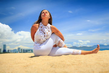 Fototapeta na wymiar girl in lace on beach in yoga asana interlaced arms behind back