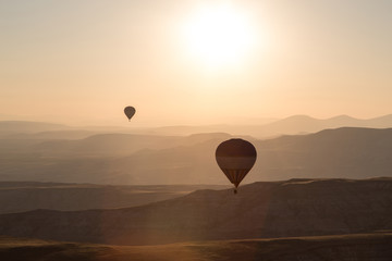 Balloons over mointains and rocks in golden cappadocia
