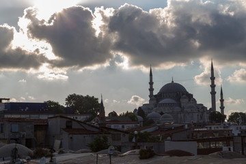 sun breaking trough clouds over istanbul's süleymaniye moscque