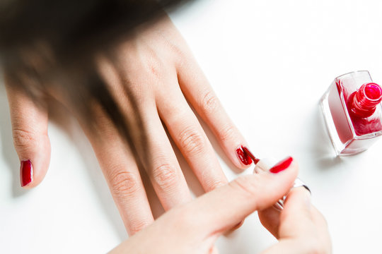 Frau lackiert ihre Fingernägel mit rotem Nagellack