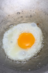 cooking fried egg in hot pan with oil