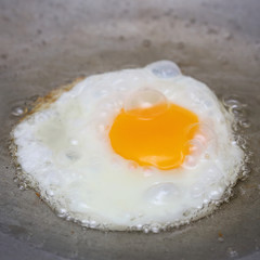 cooking fried egg in hot pan with oil