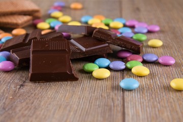 Chocolate pieces with color smarties on wooden board