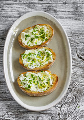 sandwiches with ricotta cheese, olive oil, pistachios and herbs is a delicious and healthy Breakfast or snack, on an oval plate on a wooden surface