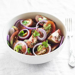 fresh salad with tomatoes in a white bowl on a light surface