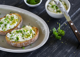 sandwiches with ricotta cheese, olive oil, pistachios and herbs is a delicious and healthy Breakfast or snack, on an oval plate on a wooden surface