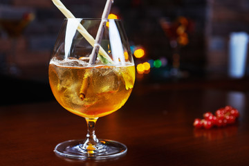 Bright strong alcoholic cocktail with a creative decoration of chocolate sticks and ice cubes on a table in a restaurant with backgrounds of colored disco lights. soft focus and beautiful bokeh.