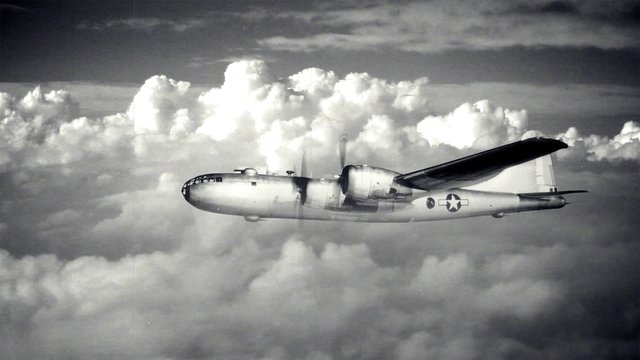 A large B-29 bomber travels above the clouds