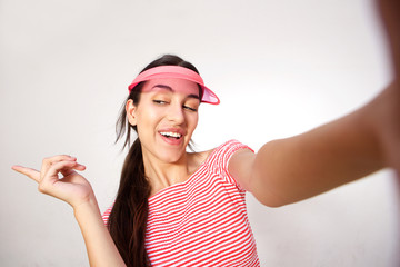Fototapeta premium Smiling young woman with pink cap taking selfie
