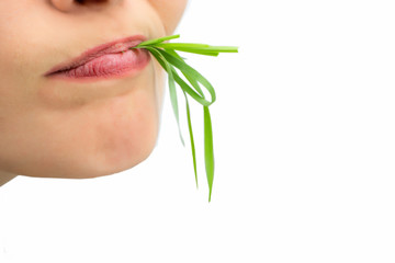 Woman with wheatgrass in her mouth, isolated on white.