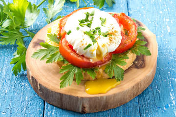 Fresh poached egg on toast with tomatoes and parsley