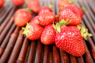 Ripe strawberries on bamboo sticks background