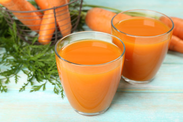 Glasses of carrot juice with vegetables on wooden background