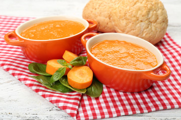 Carrot cream-soup with buns on table close up