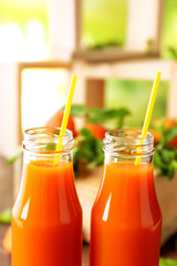 Bottles of apricot juice and fresh fruits on table close up